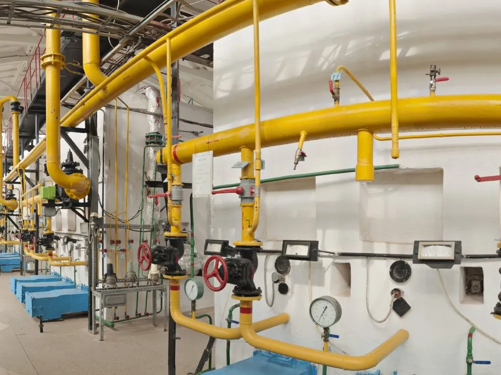 Industrial boiler room with gas piping, valves and pressure gauges